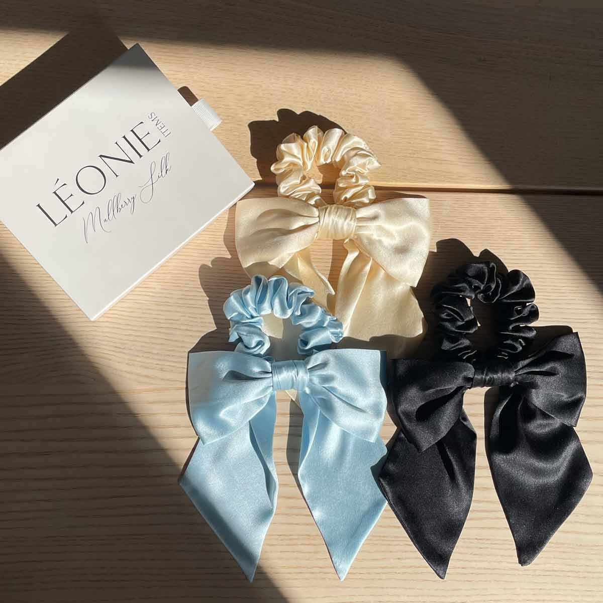 Sidenrosett-scrunchies i frägerna svart, ljusblå och champagne - 100 % mullbärssilke, stylad med Léonie Items presentask i solljus