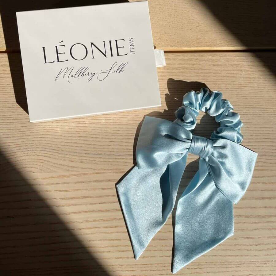 Ljusblå sidenrosett-scrunchie i mullbärssilke – stylad med Léonie Items presentask i solljus